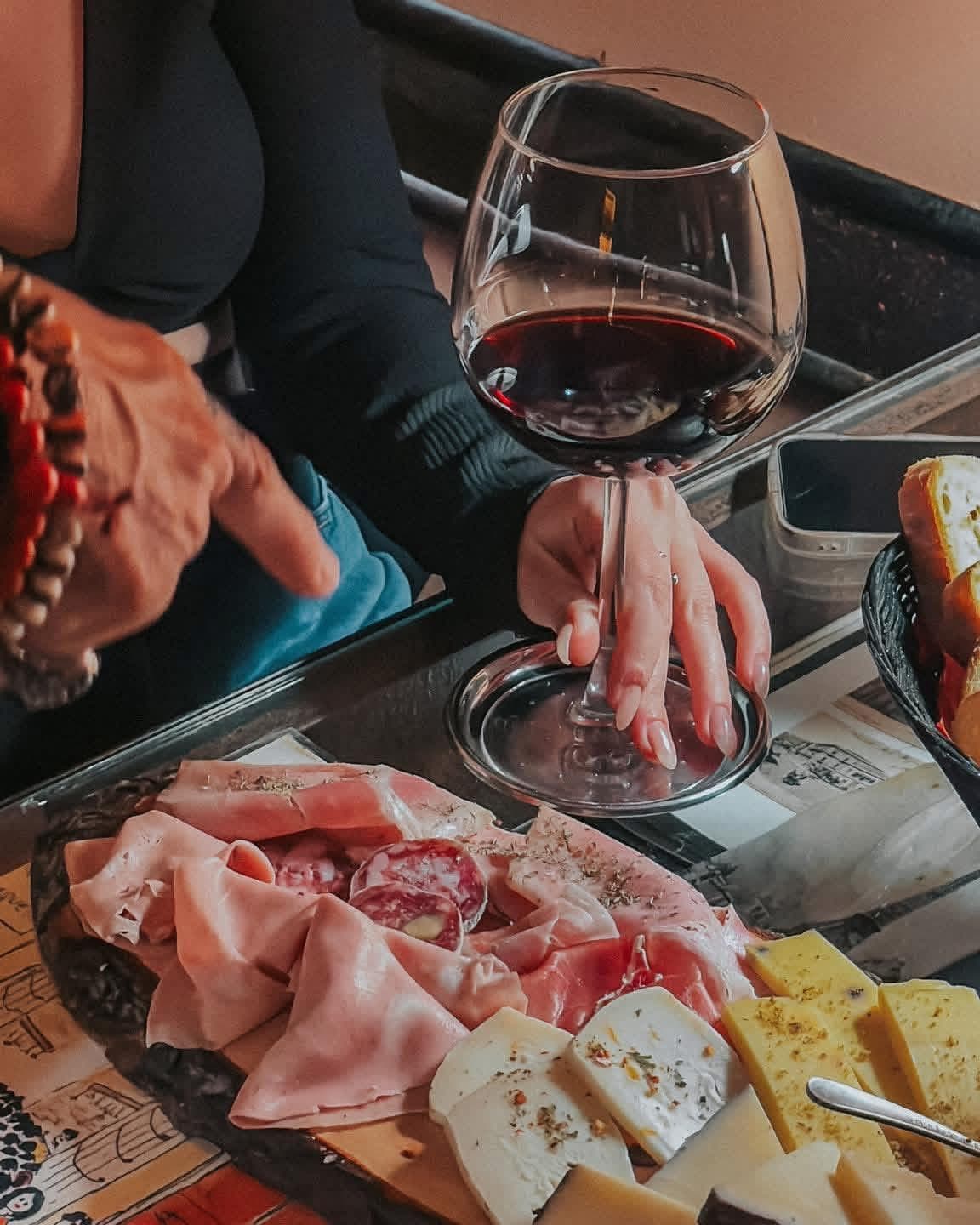 Tagliere di salumi e formaggi servito con un calice di vino rosso a Enotequa, Palermo