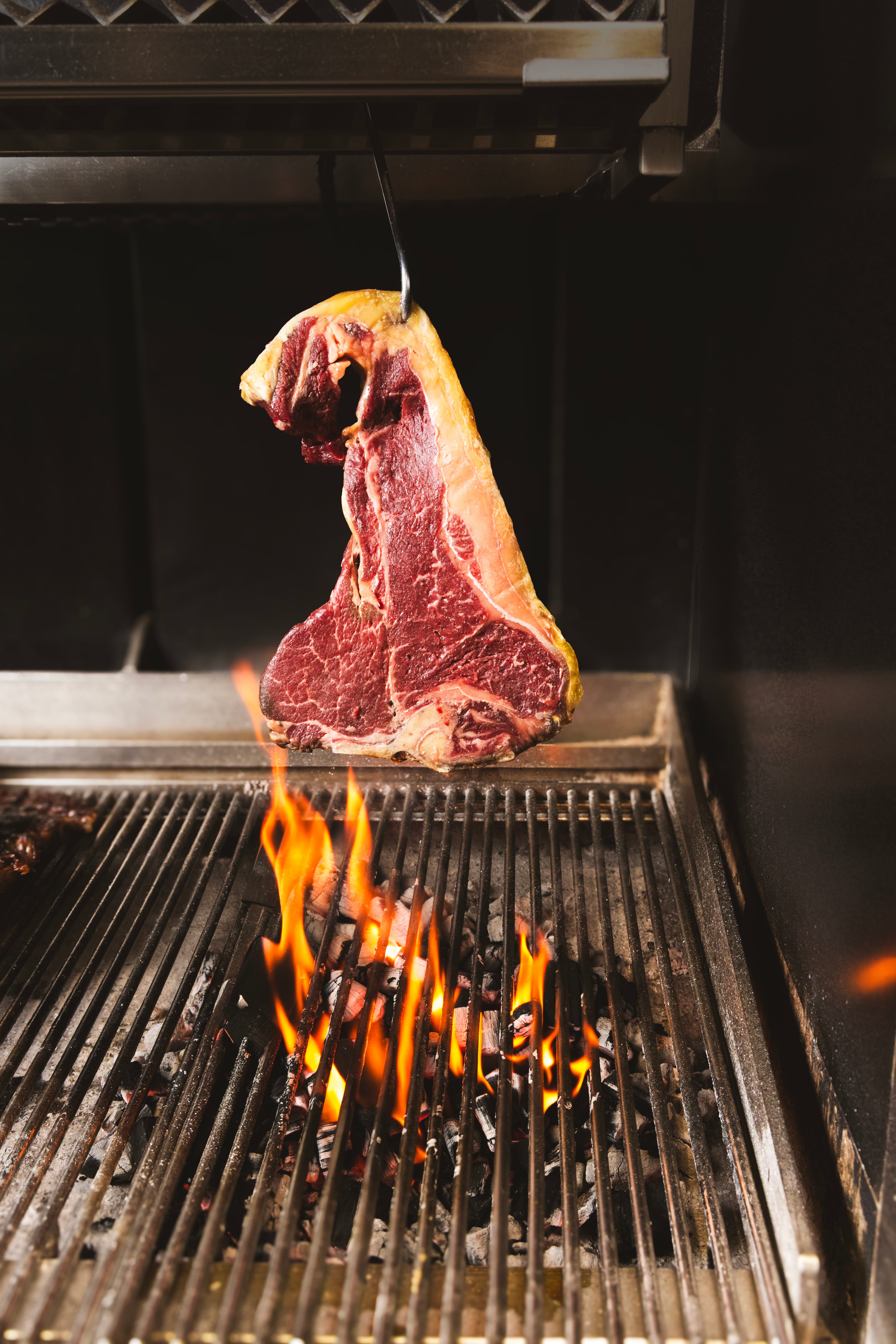 Una costata di carne in cottura sulla brace al ristorante Matigusta