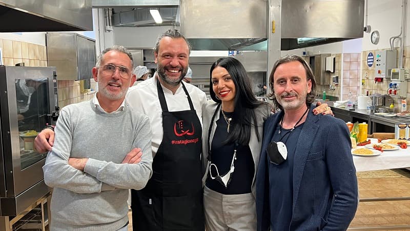 I soci de La Brigata di Goa in cucina insieme a uno chef con grembiule, sorridenti